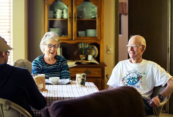 Elderly woman and man sitting at a table smiling.