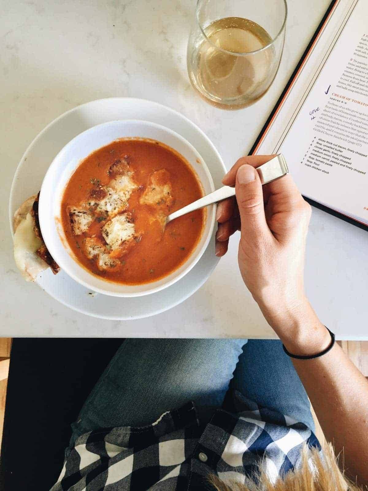 hand holding a spoon in a bowl of soup