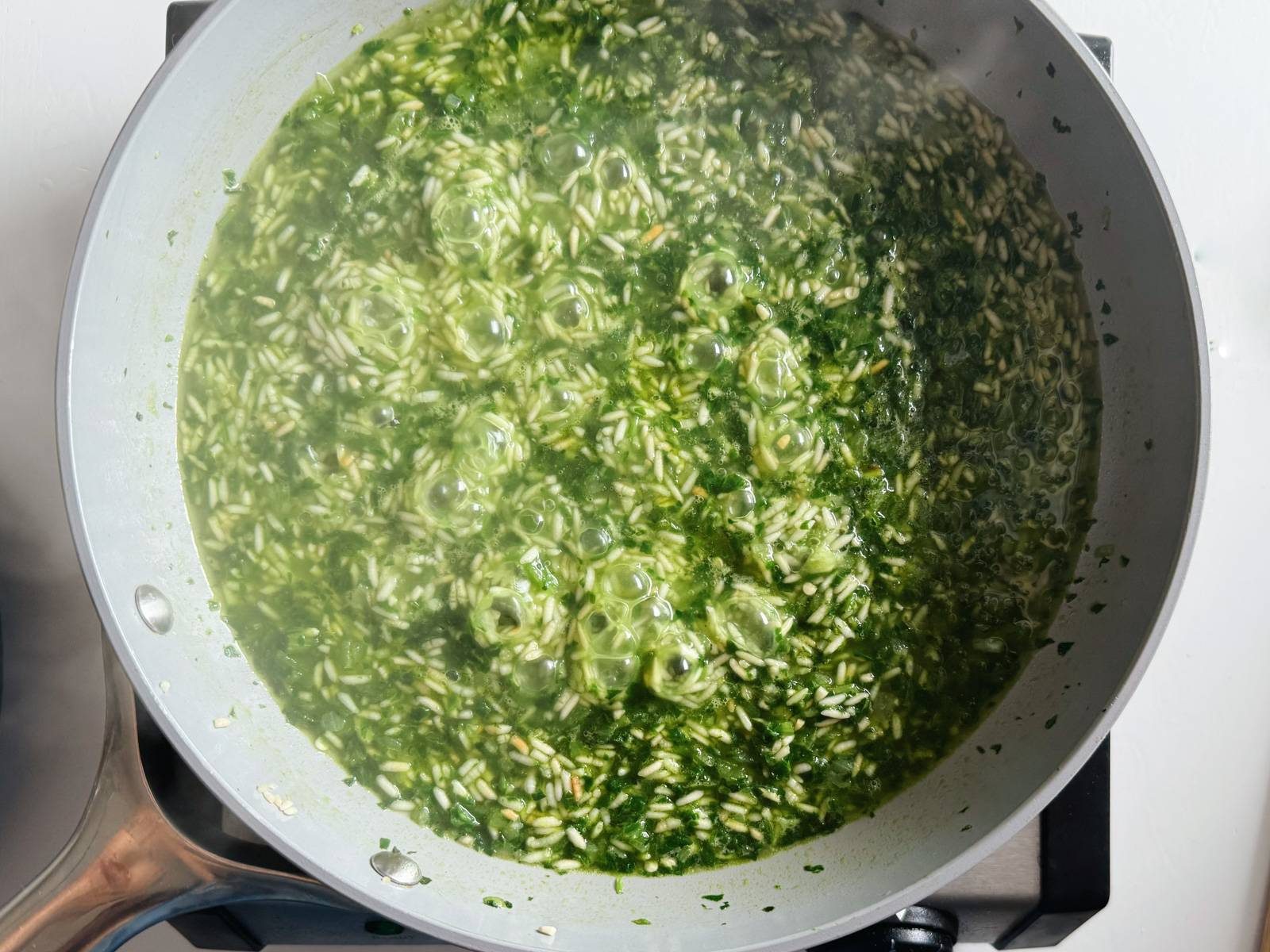 Simmering green rice in a pan.