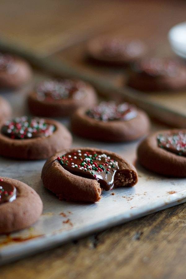 Chocolate thumbprint cookies with sprinkles on a baking pan.