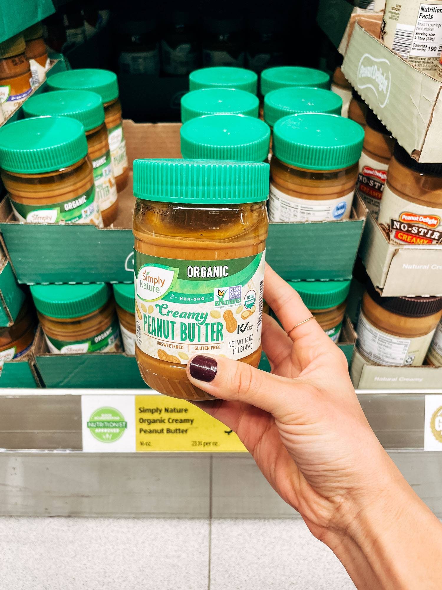 White hand holding a jar of peanut butter