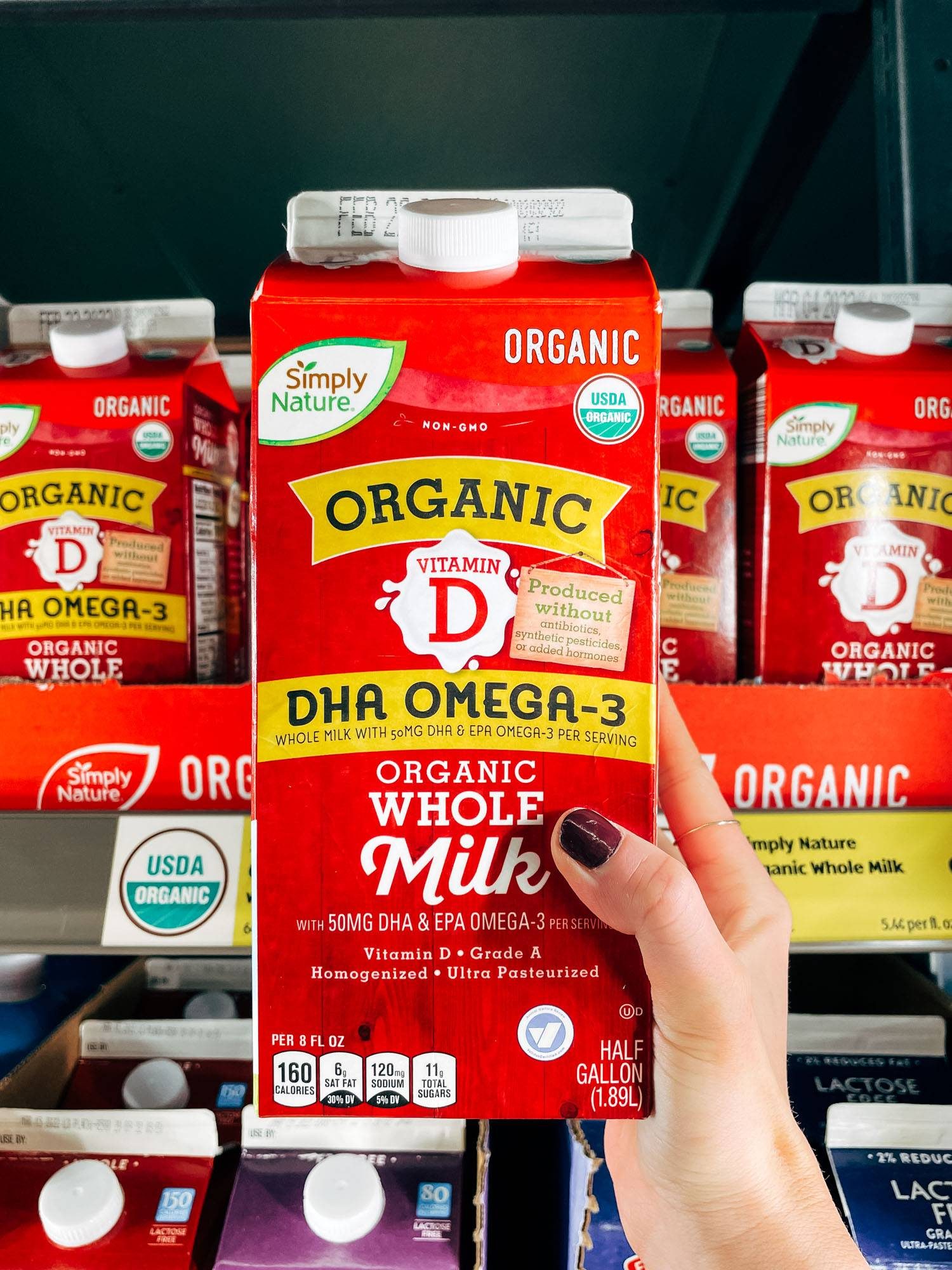 White hand holding a container of whole milk