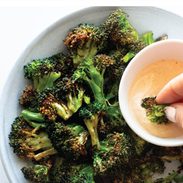 Air fryer broccoli in a bowl with sauce on the side.