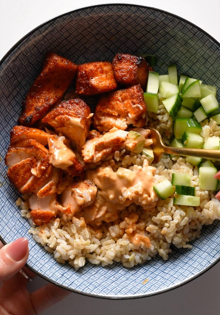 Air fryer salmon in a bowl with rice and cucumbers.