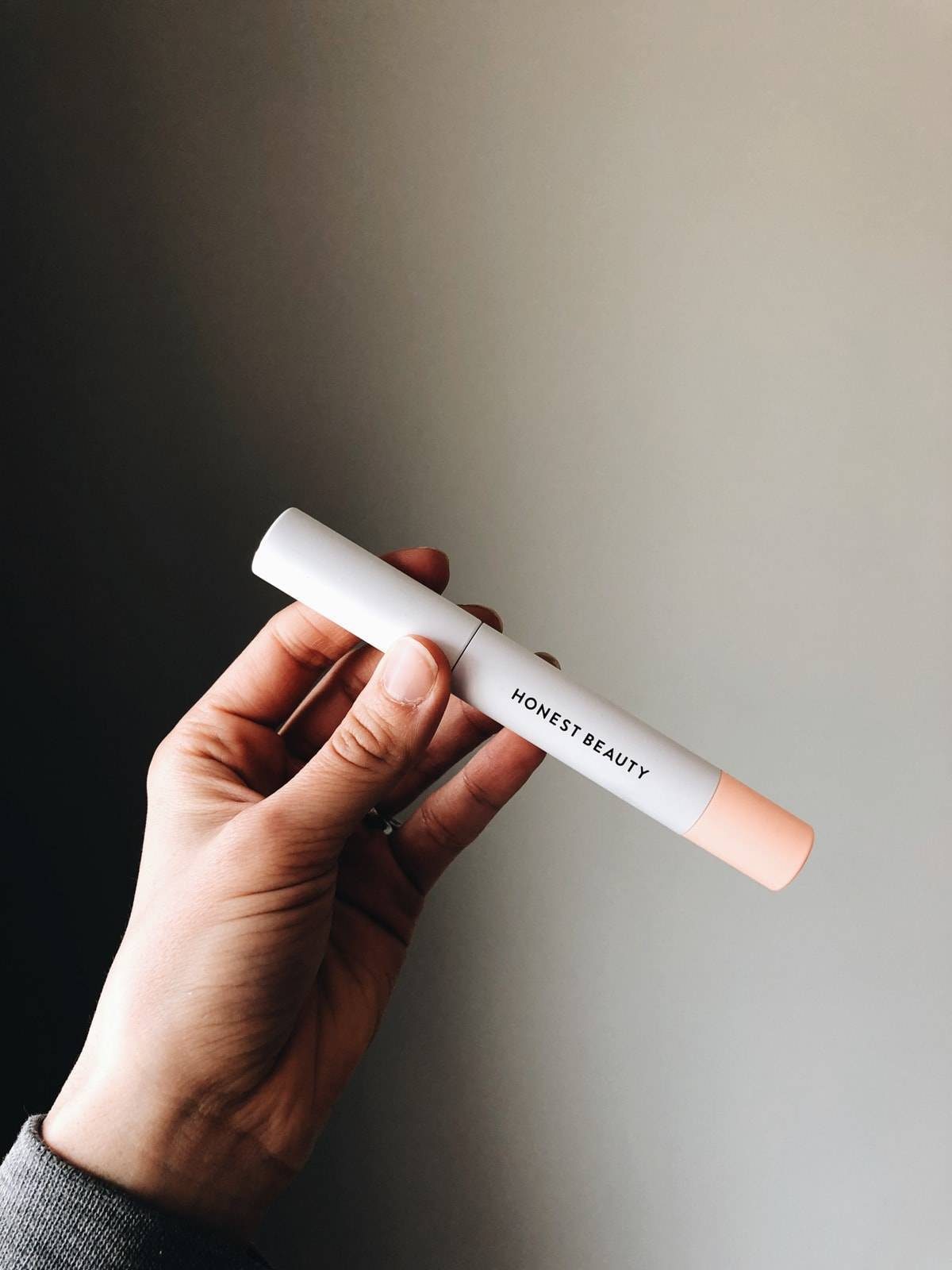 A person holding a white tube in their left hand.