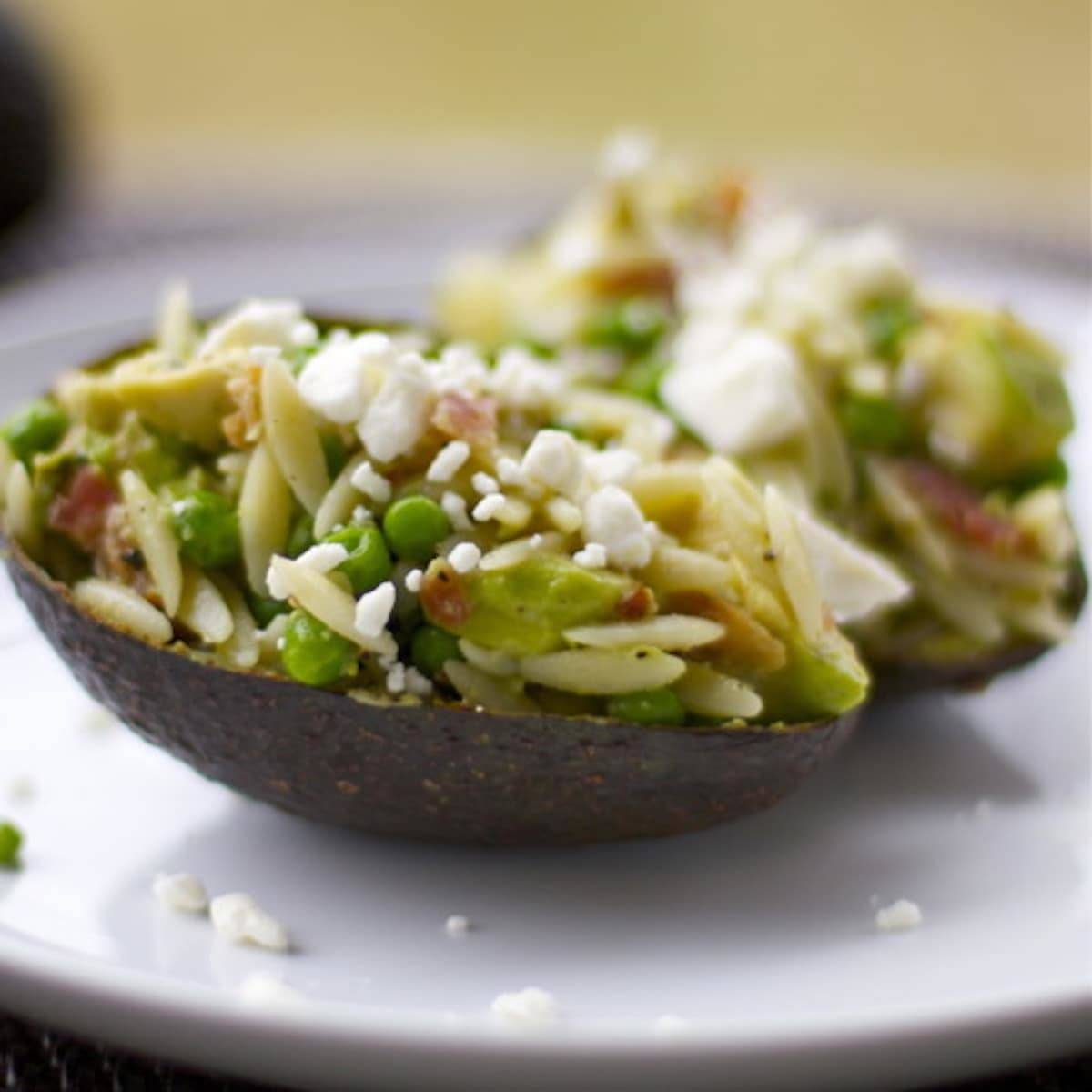 Avocado Bacon Orzo with feta cheese served in an avocado peel.