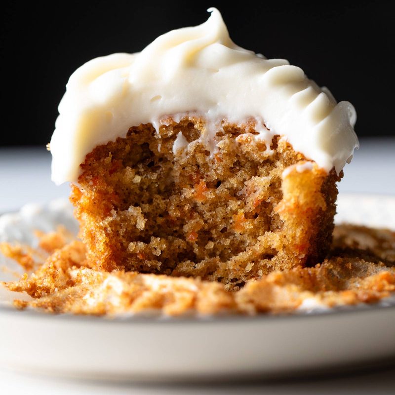 Carrot cake cupcake with cream cheese frosting on a plate.