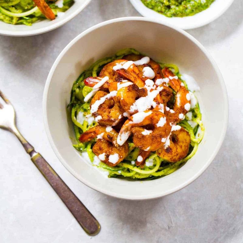 Two bowls havewith shrimp next to sauce.