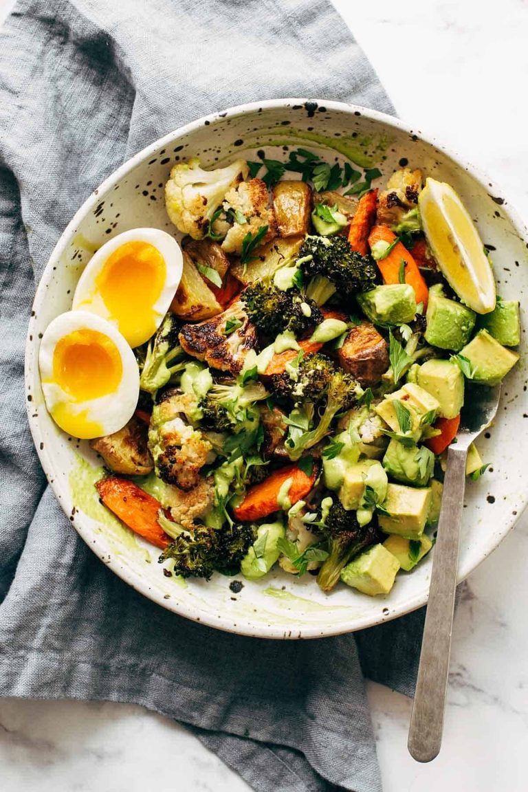 Roasted vegetables in a bowl with green tahini.