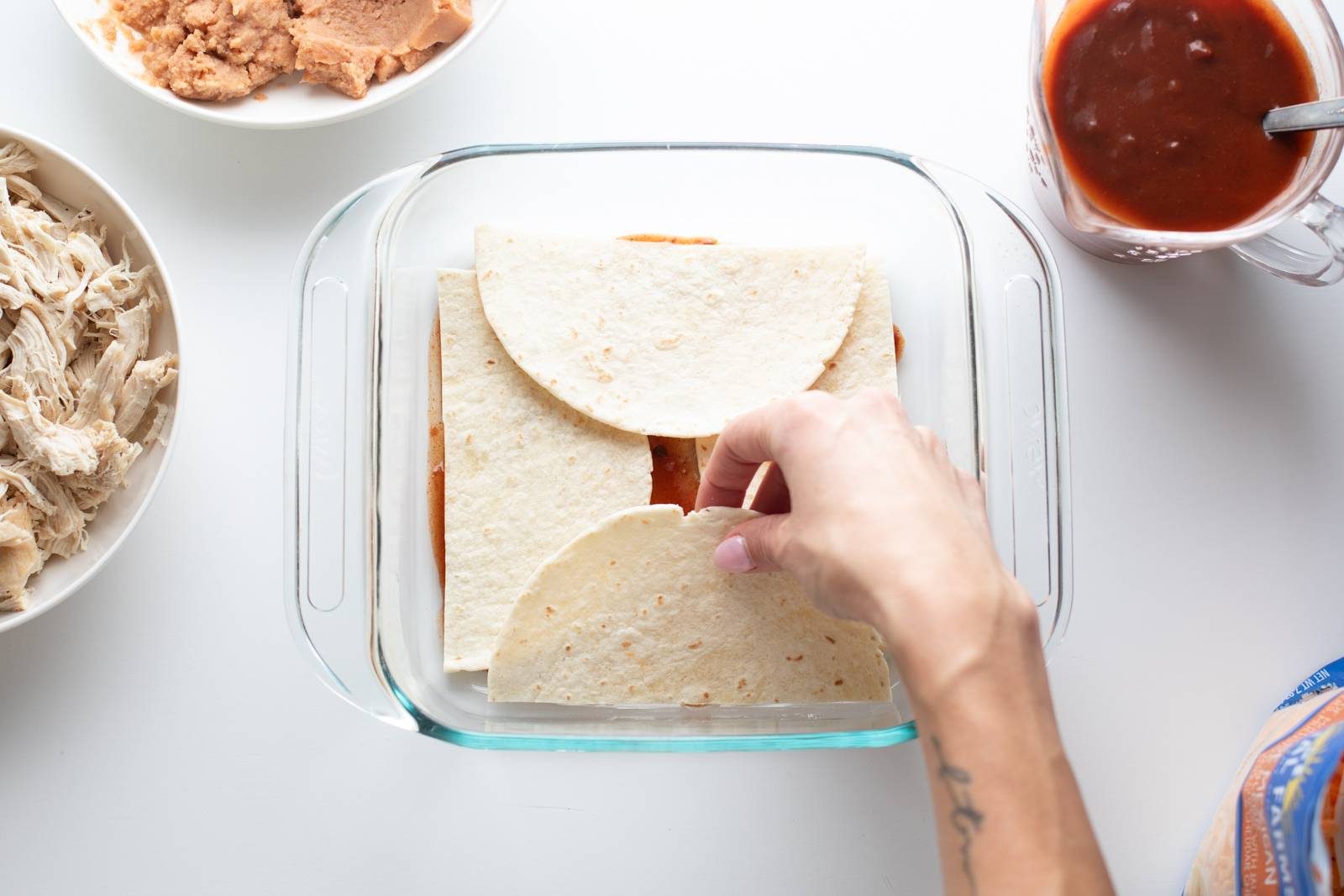 Layering tortillas in a glass baking dish.