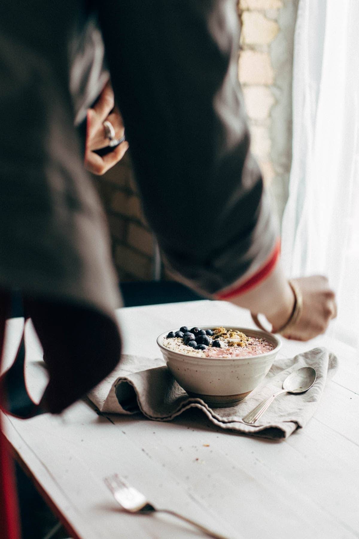 Woman styling a smoothie bowl on a napkin.